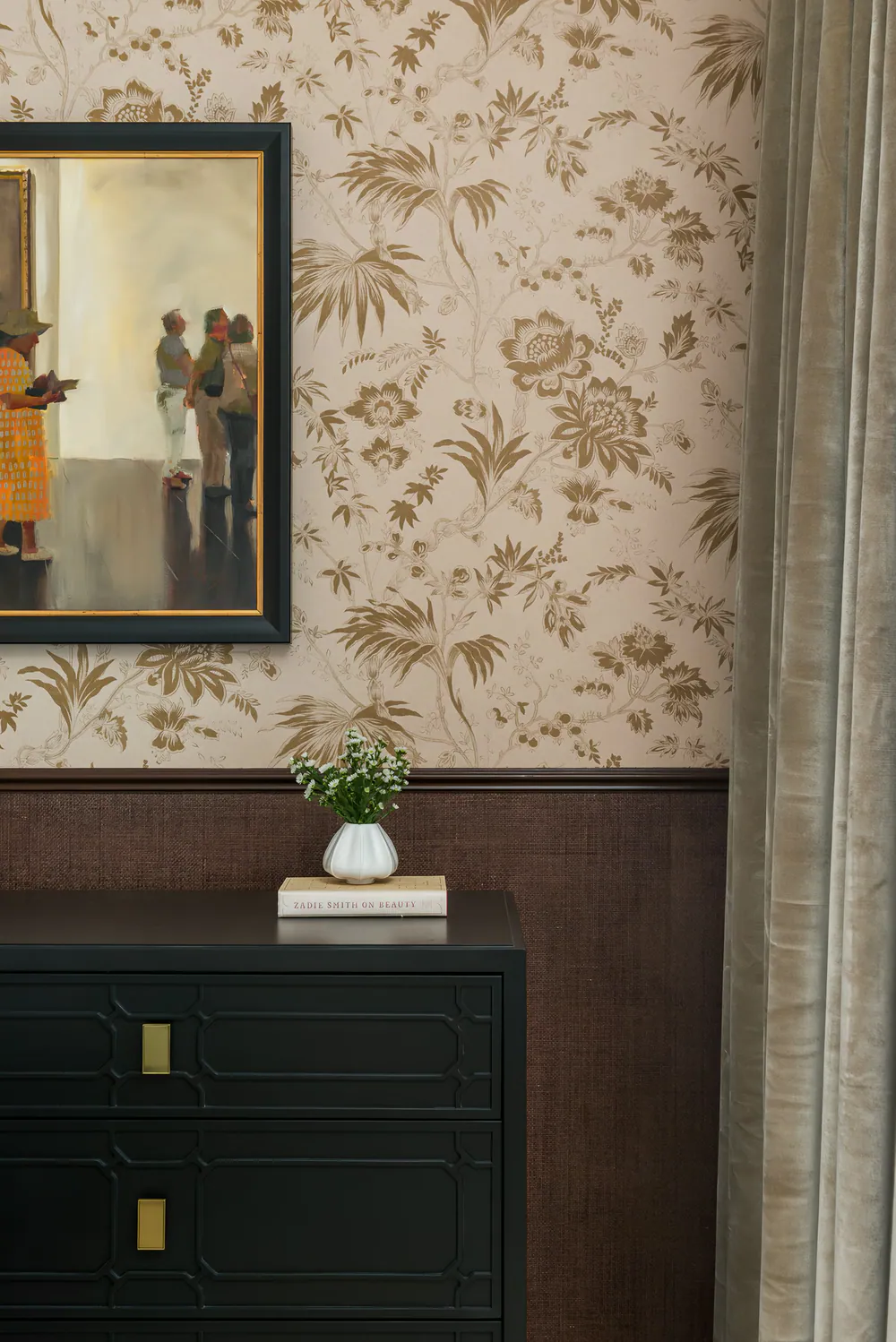 Bedroom vignette with a gallery painting above a black fretwork chest, floral wallpaper, grasscloth wainscot and velvet drapery, at Art House in Downtown St. Petersburg. Interior design by MJ Designs