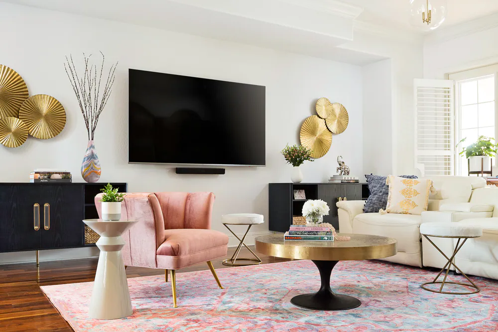 Living room with blush velvet chair, brass sunburst wall discs, white leather sectional and pastel rug, at Bayou Grande in St. Petersburg. Interior design by MJ Designs