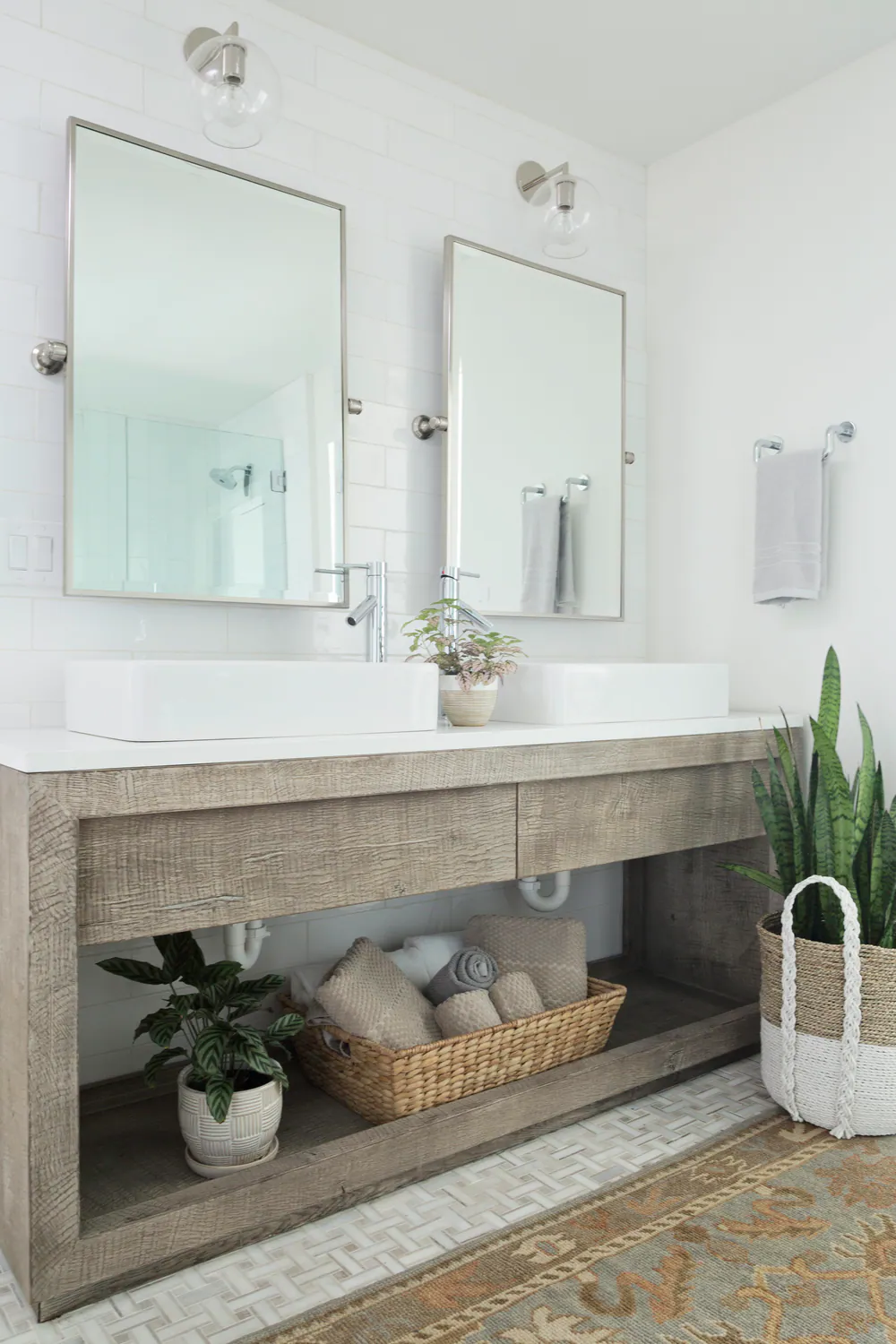Bathroom with a weathered wood double vanity, vessel sinks and white subway tile, at Bayshore in Tampa. Interior design by MJ Designs