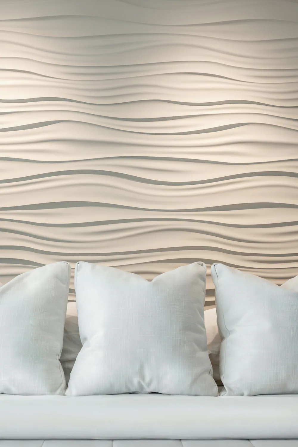 Sculpted white wave wall panel behind white linen pillows, at Gulf Beaches Condo in Pinellas County. Interior design by MJ Designs