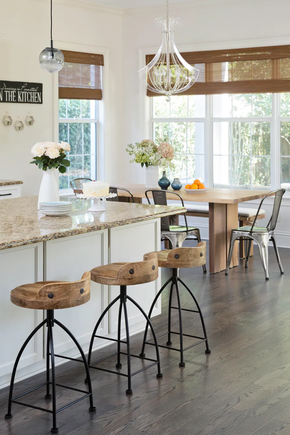 Kitchen island with granite top and wood saddle stools, breakfast table beyond, at Hyde Park in Tampa. Interior design by MJ Designs