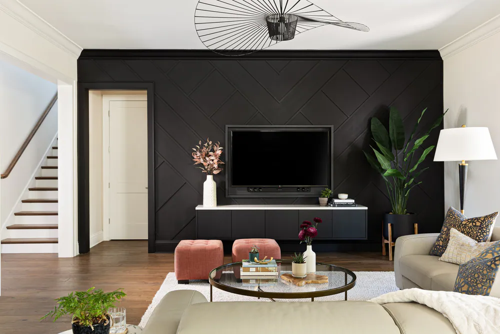 Family room with a black chevron-paneled media wall, blush velvet ottomans and a wire pendant, at Snell Isle in St. Petersburg. Interior design by MJ Designs